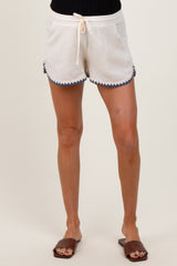 woman wearing white maternity shorts with blue scalloped detailing and drawstring waist
