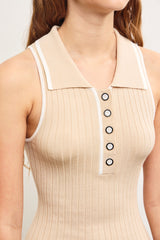woman wearing a beige ribbed sleeveless polo dress with a collared neckline and black button details