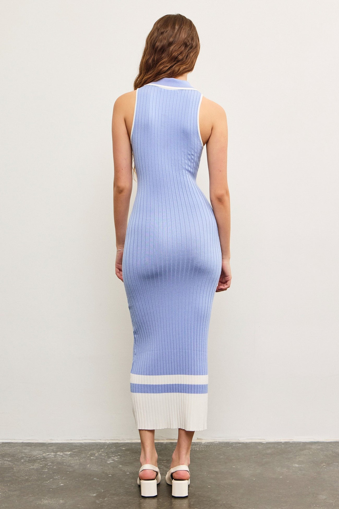 woman wearing a fitted ribbed knit midi dress in light blue with white stripes on the hem and neckline