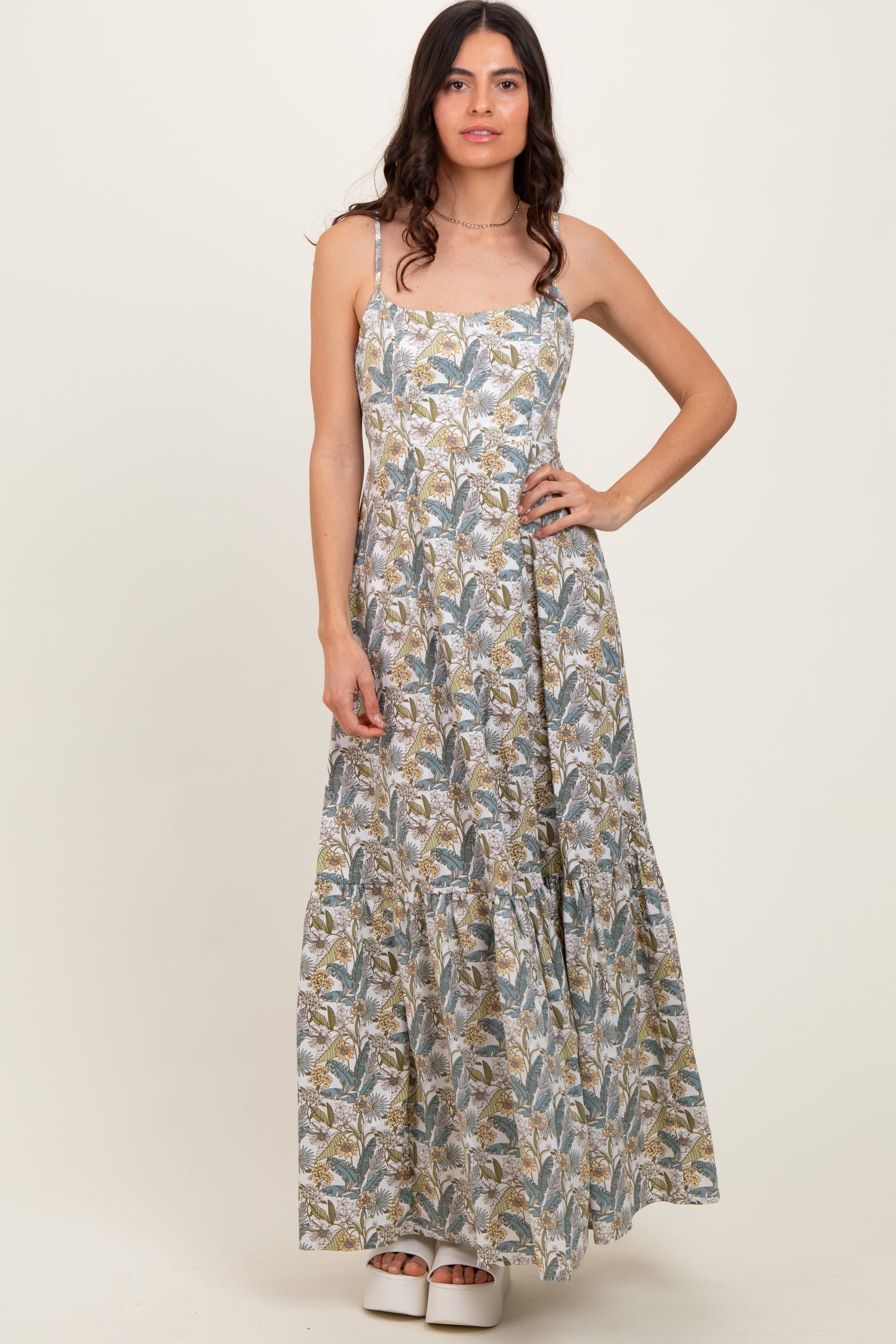 woman wearing a floral print maxi dress with spaghetti straps and a tiered skirt