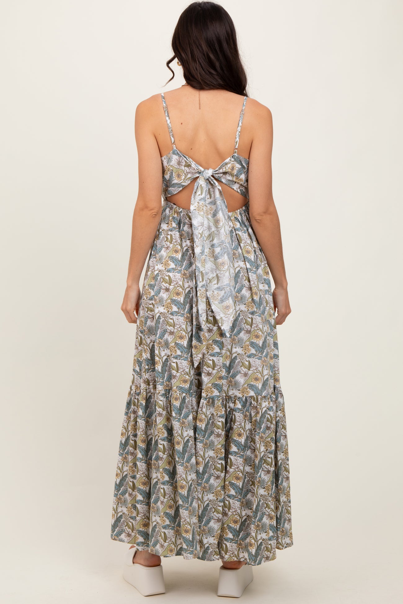 woman wearing a backless floral maxi dress with a tied bow detail and a tiered skirt