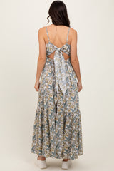 woman wearing a backless floral maxi dress with a tied bow detail and a tiered skirt