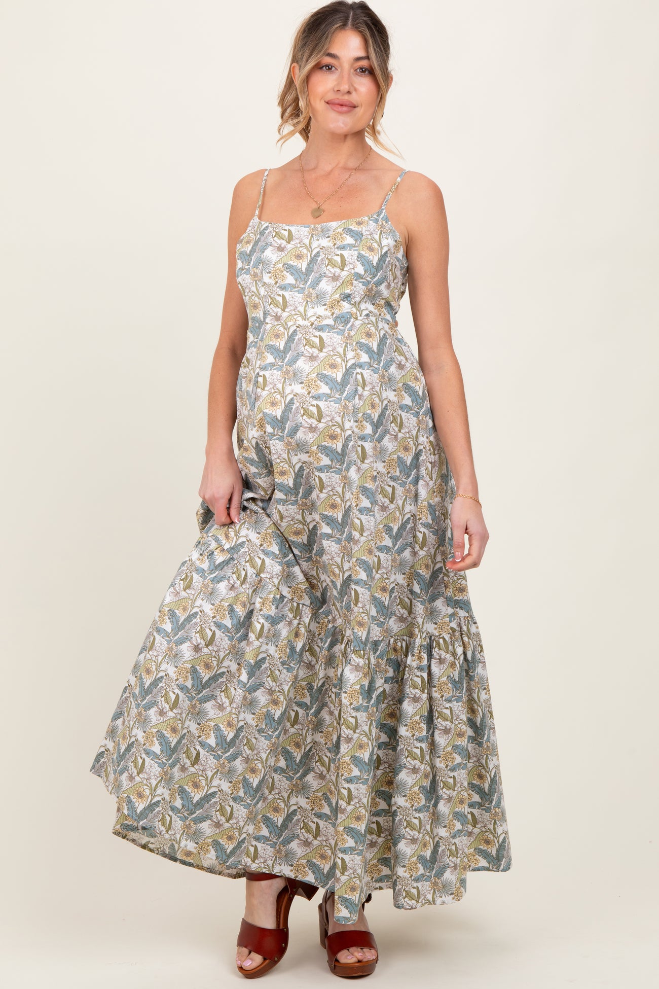 woman wearing a floral patterned maxi maternity dress with adjustable straps and a baby bump visible