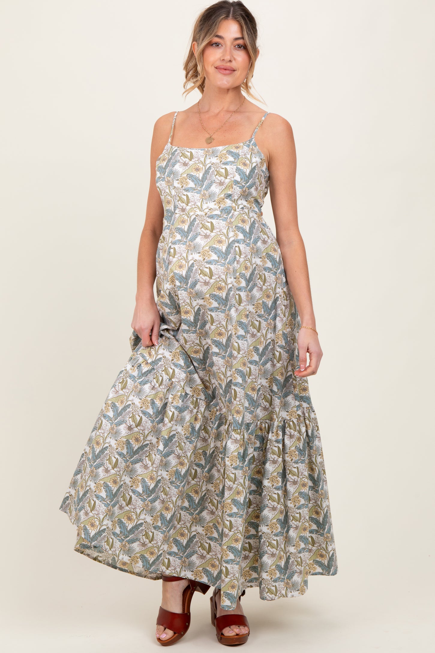 woman wearing a floral patterned maxi maternity dress with adjustable straps and a baby bump visible