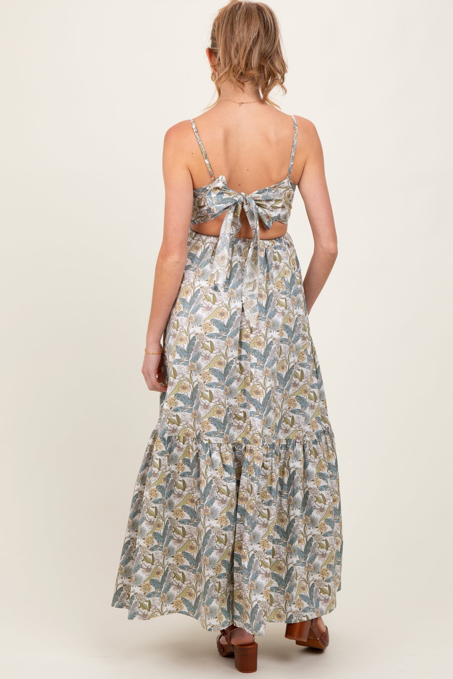woman wearing a floral print maternity maxi dress with a tie back and tiered hem