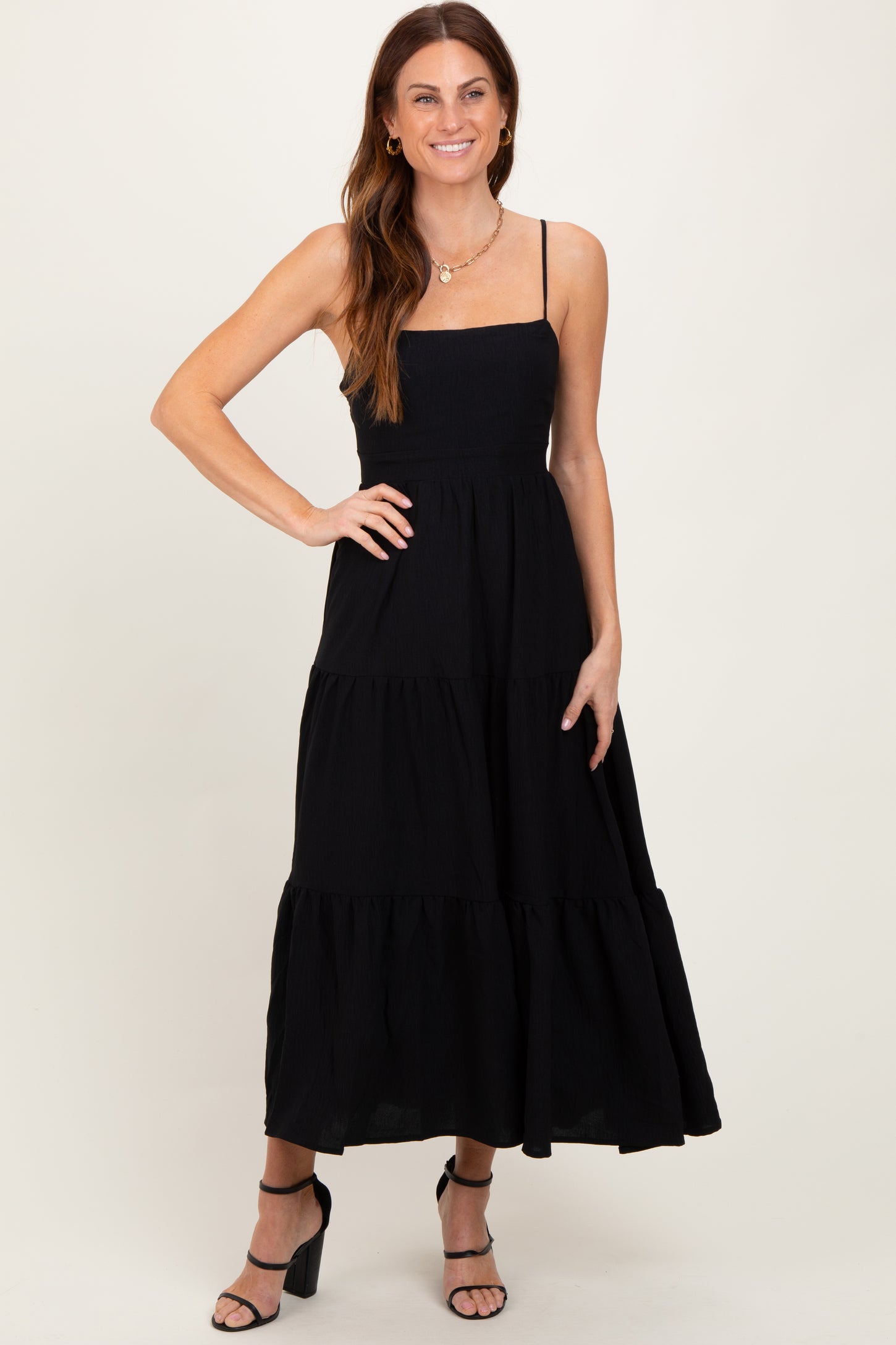 woman wearing a black sleeveless maxi dress with tiered ruffle details and a fitted bodice
