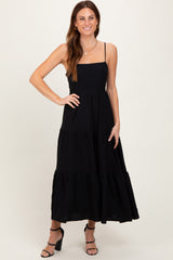 woman wearing a black sleeveless maxi dress with tiered ruffle details and a fitted bodice