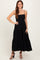 woman wearing a black sleeveless maxi dress with tiered ruffle details and a fitted bodice
