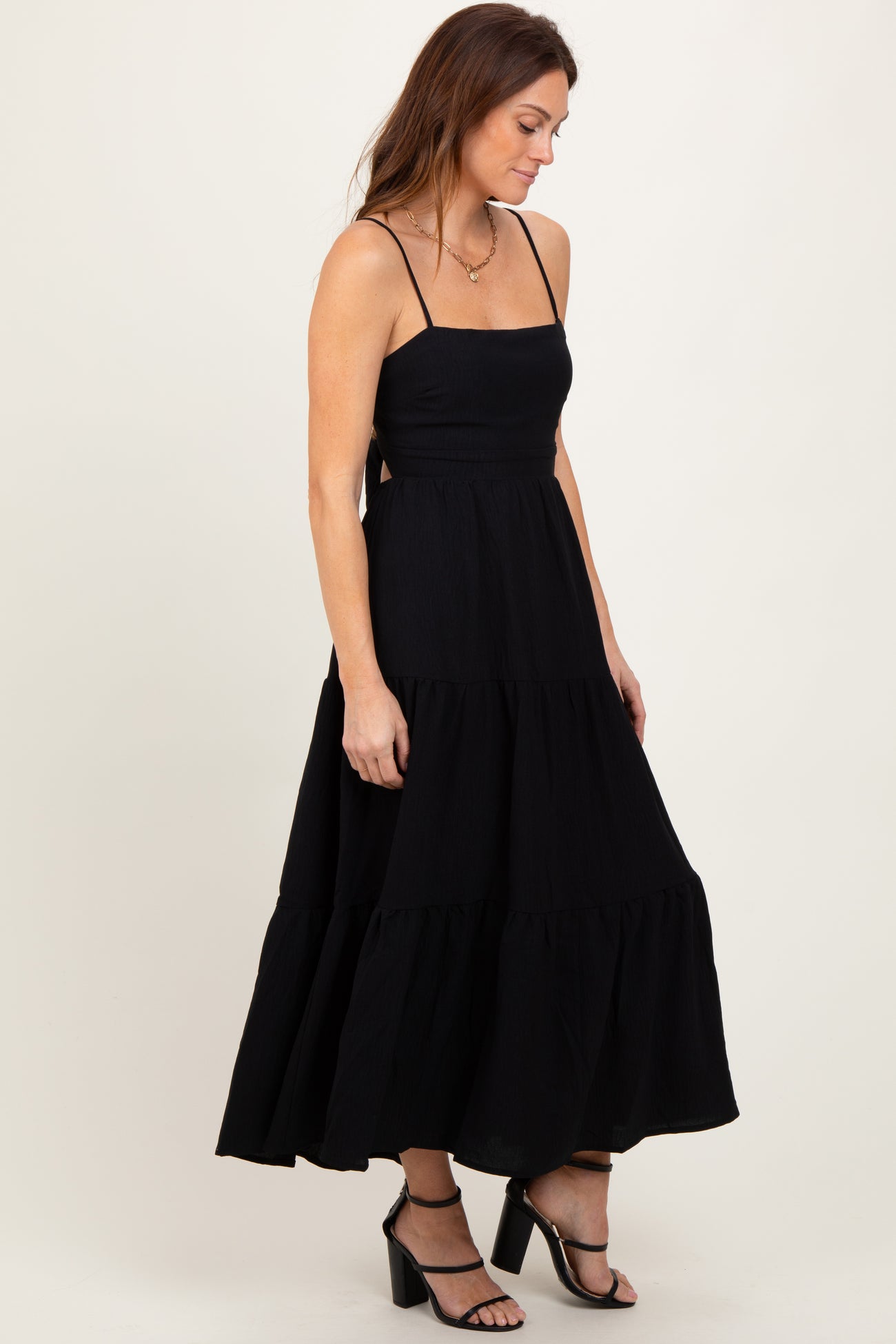 woman wearing a black tiered maxi dress with spaghetti straps and a fitted bodice