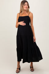 woman wearing a black tiered maternity dress and holding her baby bump