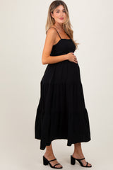 woman wearing a black tiered maternity dress and holding her baby bump