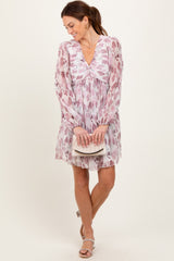 woman wearing a pink floral long sleeve dress with a v-neck and holding a small clutch purse