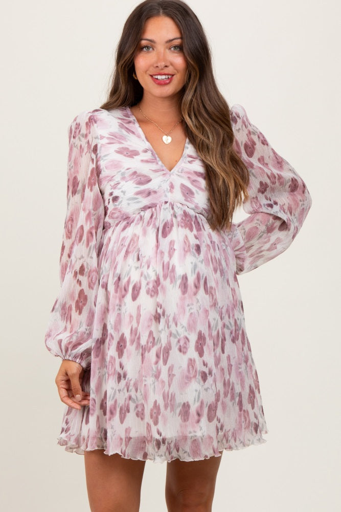 woman wearing a pink and purple floral maternity dress with a v-neckline and long sleeves, showcasing her baby bump