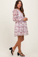 woman wearing a pink floral maternity dress with puff sleeves and a v-neckline, showcasing her baby bump