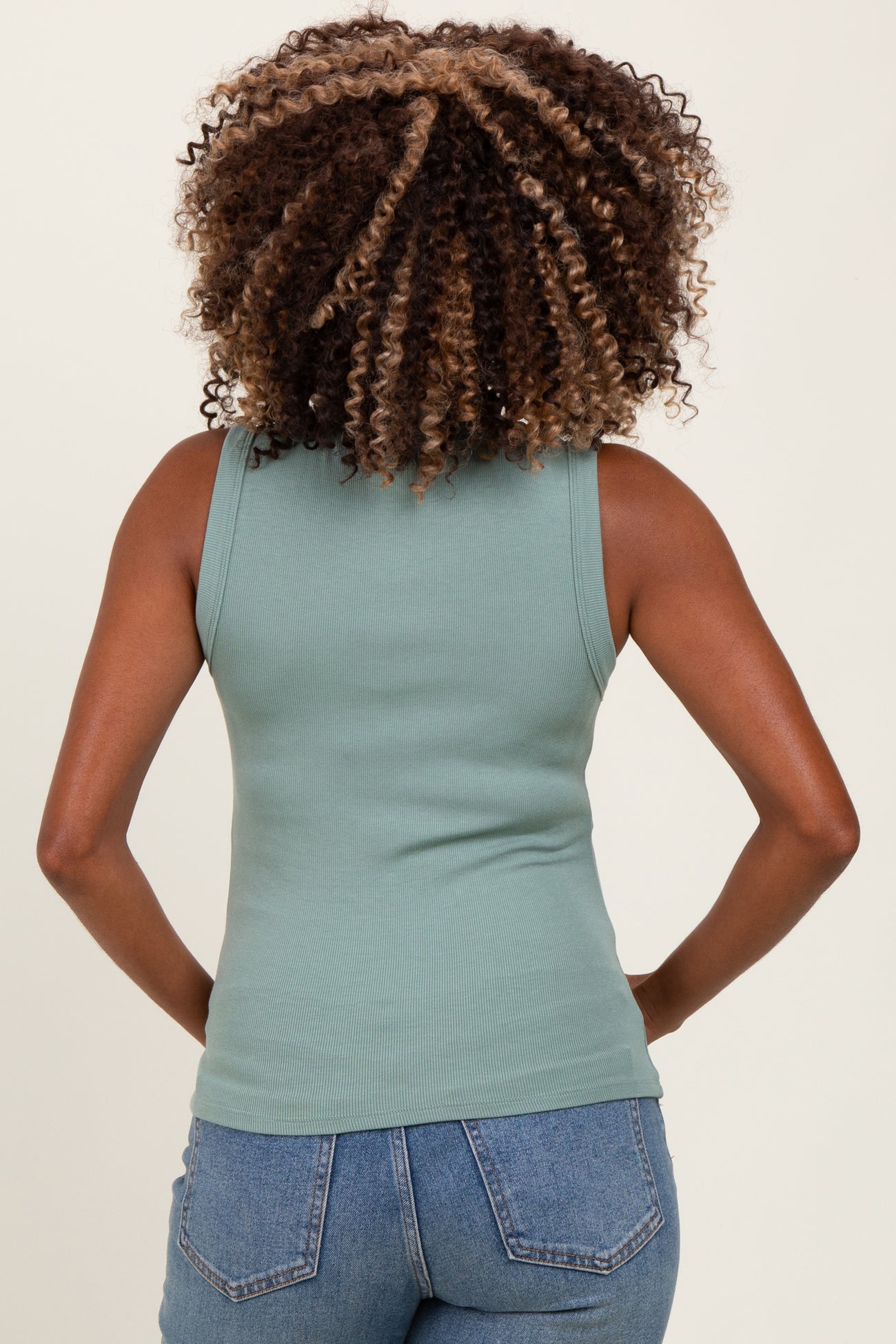 woman wearing a mint green sleeveless maternity tank top, viewed from the back, showing a relaxed fit and ribbed texture