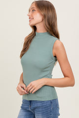 woman wearing a fitted green sleeveless mock neck top with a ribbed texture and blue jeans