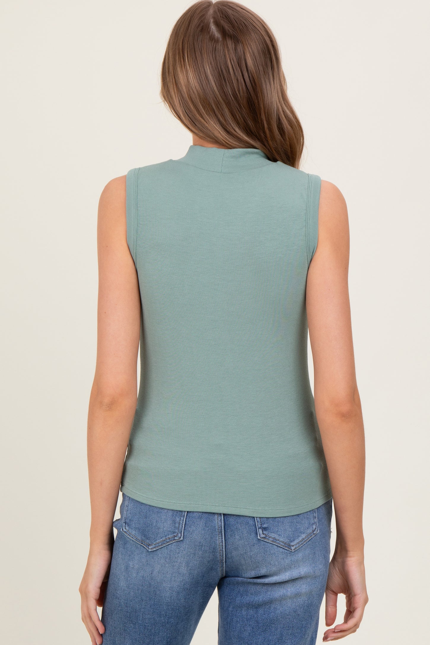 woman wearing a sleeveless light green ribbed top from the back with casual blue jeans