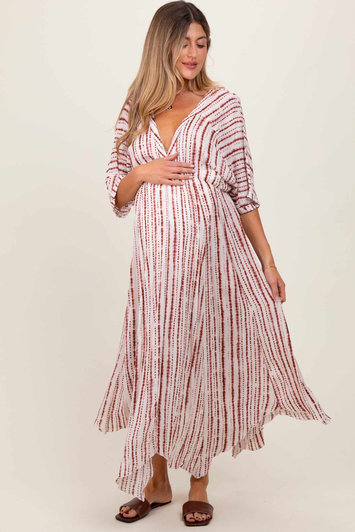woman wearing a long white and red striped maternity dress and holding her baby bump