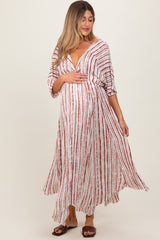 woman wearing a long white and red striped maternity dress and holding her baby bump