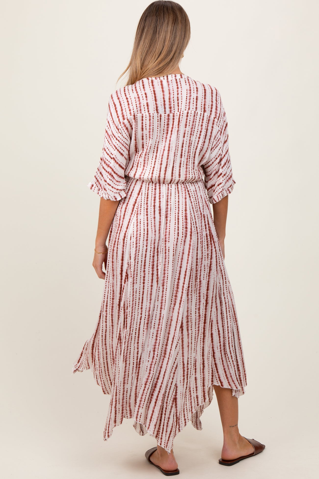 woman wearing a red and white striped maternity maxi dress with three-quarter sleeves and a tie waist, seen from the back