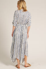 woman wearing a back view of a white and blue striped maxi dress with an asymmetrical hem and three-quarter sleeves