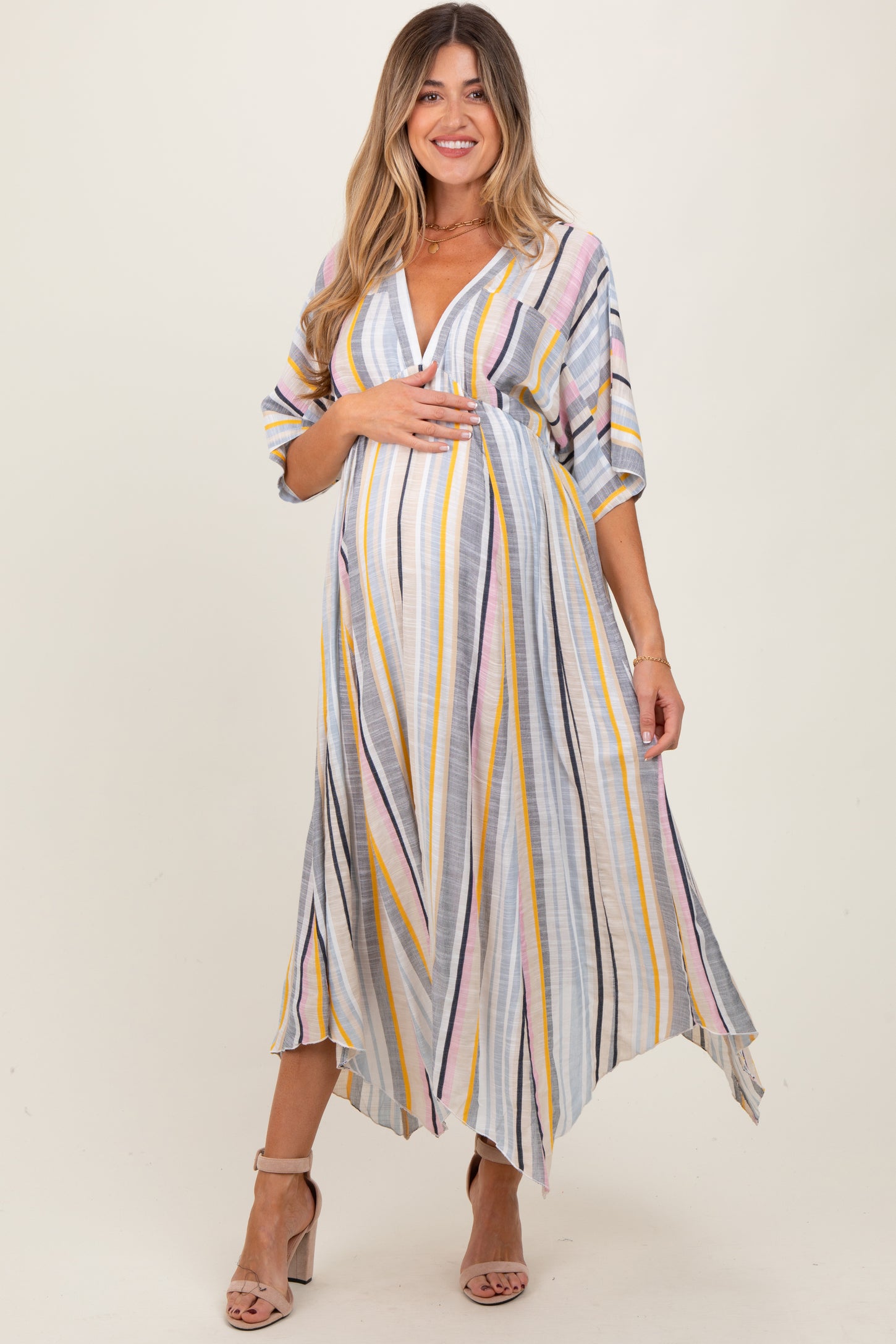 woman wearing a grey striped maternity dress with a deep v-neck and elbow-length sleeves, holding her baby bump