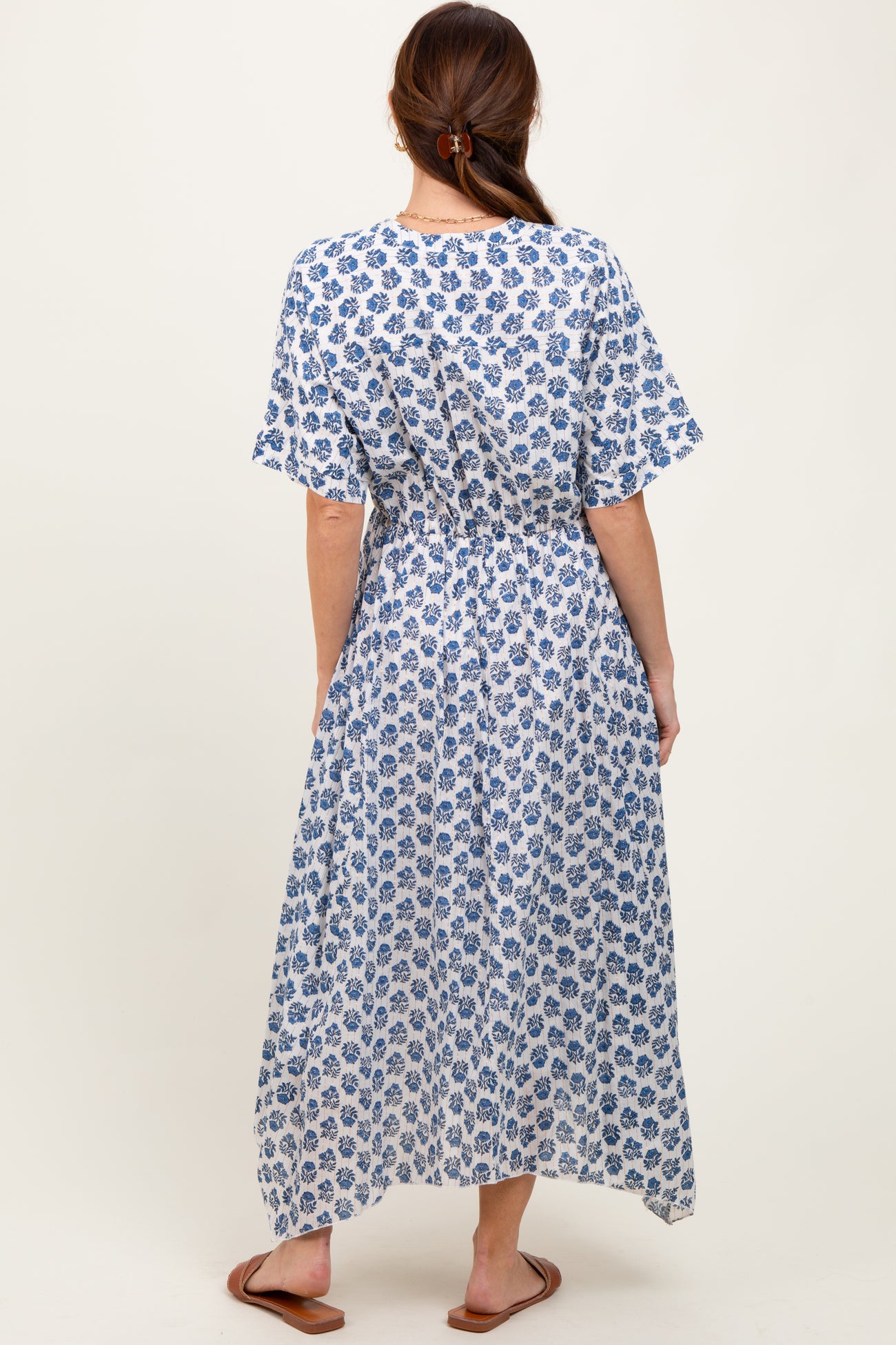 woman wearing a blue and white floral maxi dress with short sleeves and an elastic waist, viewed from the back