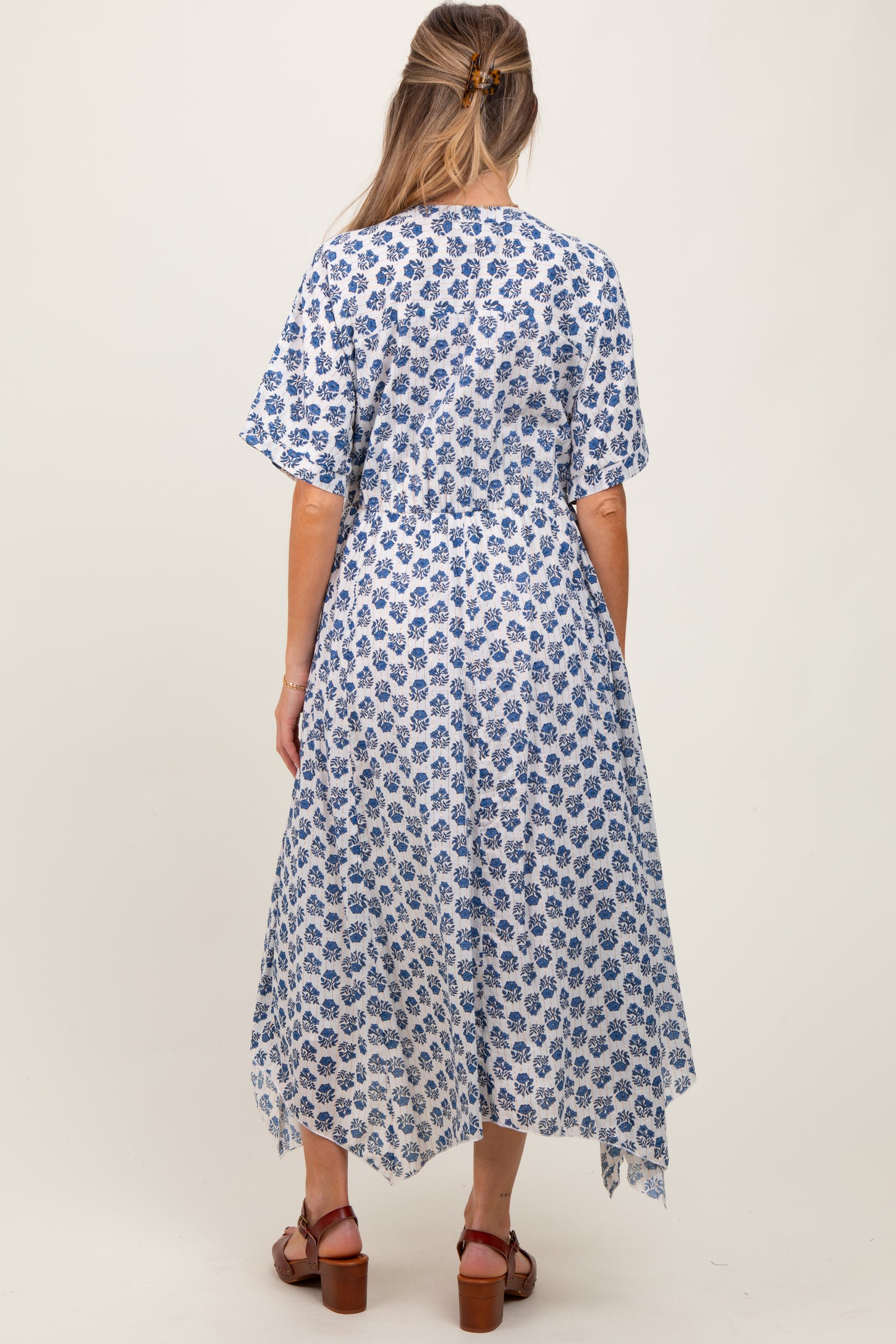 woman wearing a blue and white floral print maternity dress with short sleeves and an asymmetrical hemline