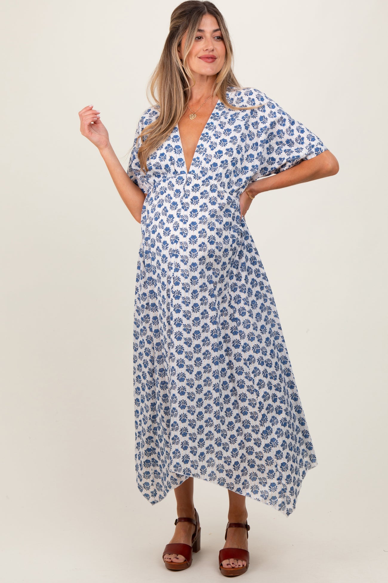 woman wearing a white floral print maternity dress with a deep v-neck and short sleeves, showcasing her baby bump
