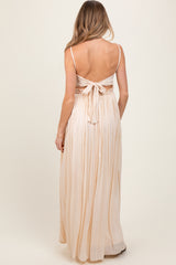 woman wearing a light peach maternity maxi dress with a tie back and flowing skirt, seen from the back