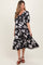 woman wearing a black floral maternity dress with puff sleeves and a flowing skirt, showcasing her baby bump