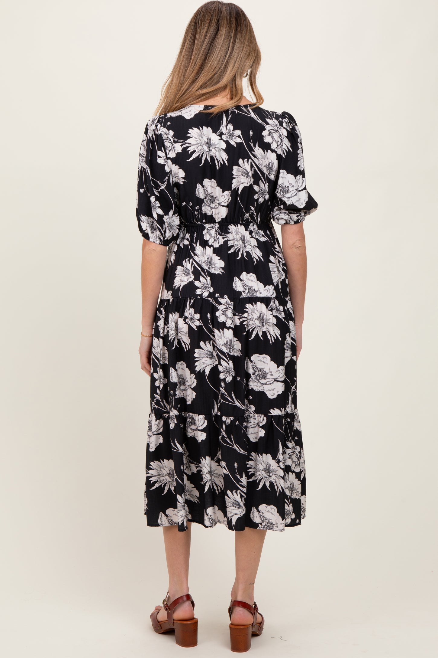 woman wearing a black floral print maternity dress with short puff sleeves and a cinched waist