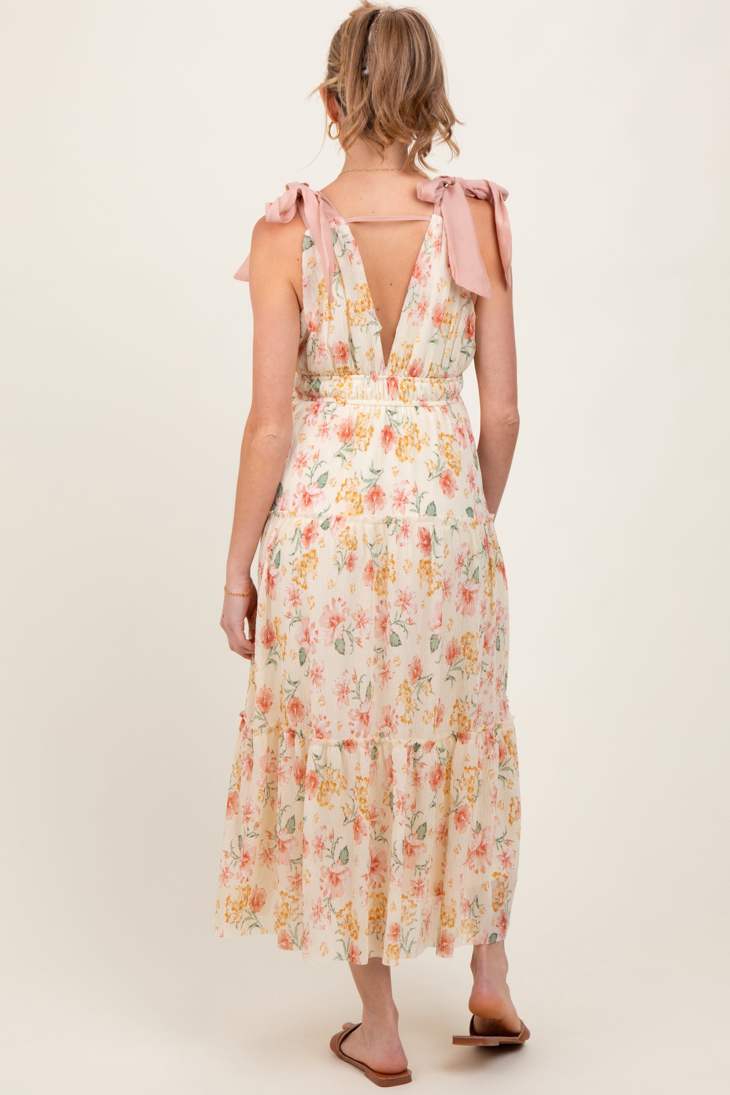 woman wearing a floral print maternity dress with tie shoulder straps and a backless design