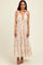 woman wearing a floral maxi dress with pink tie straps and a plunging neckline, standing against a neutral background