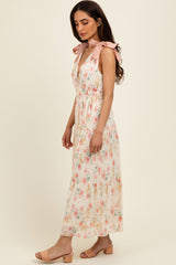 woman wearing a floral maxi dress with pink tie straps and a tiered skirt, styled with beige block heel sandals