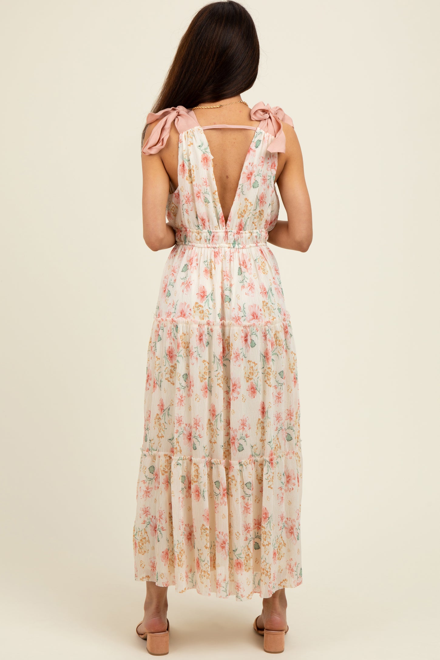 woman wearing a floral long maxi dress with adjustable bow straps and a low back design