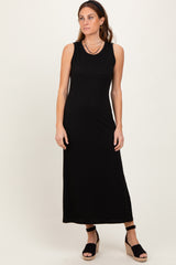 woman wearing a black sleeveless maxi dress with a textured fabric and standing in black wedge sandals