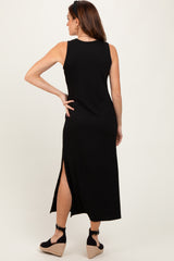 woman wearing a black sleeveless maxi dress with a side slit, showing the back view and a pair of wedges