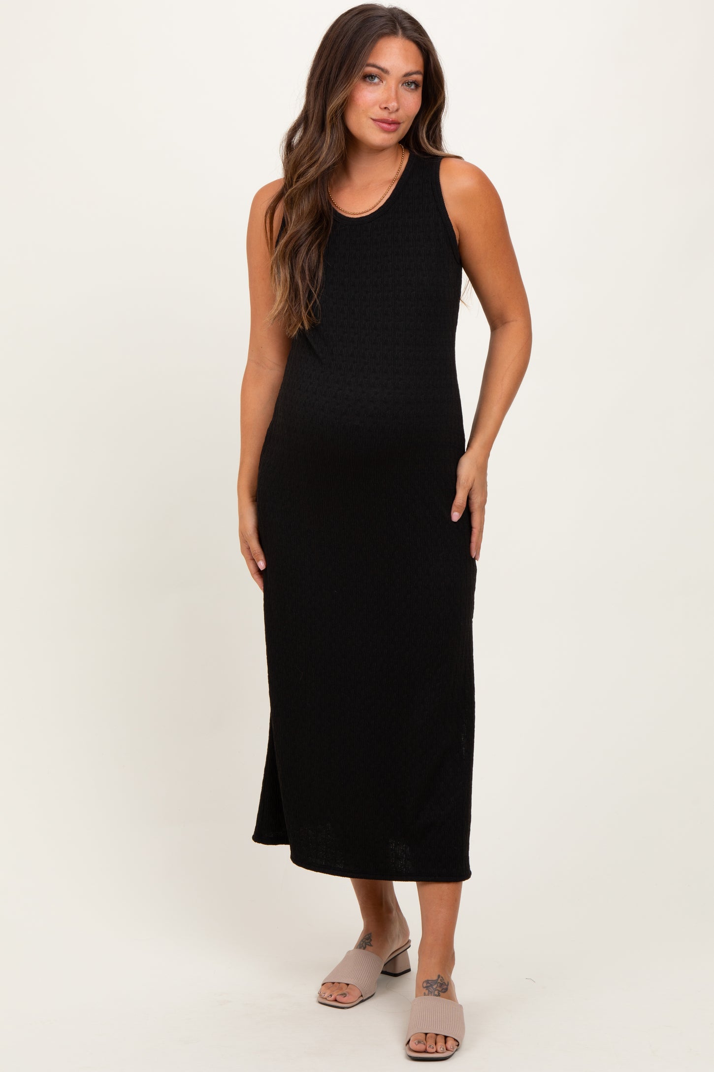 woman wearing a black sleeveless maternity maxi dress and showing her baby bump