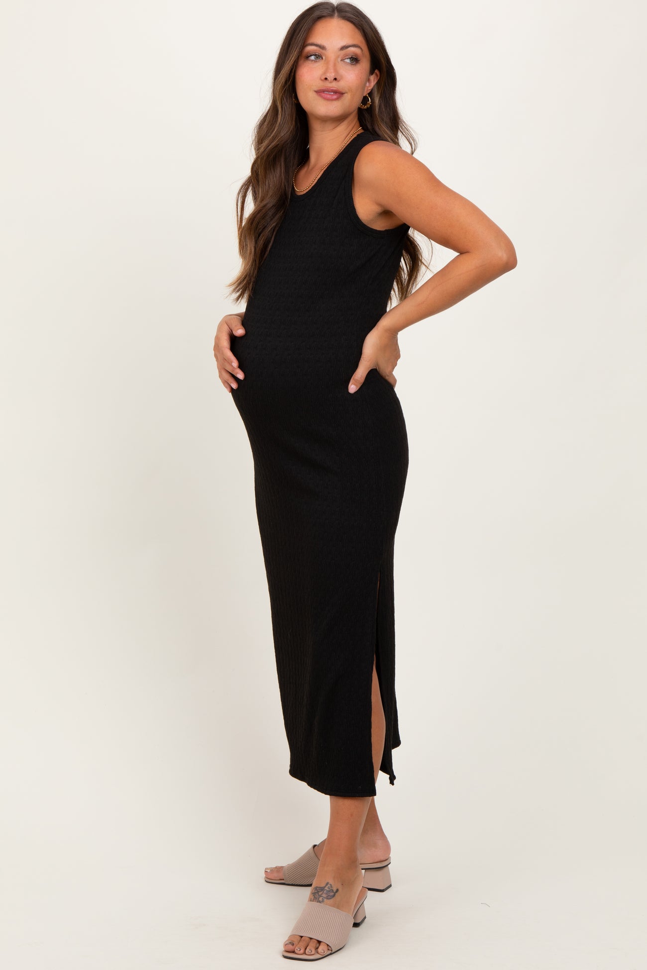 woman wearing a black ribbed maternity dress with side slits and highlighting her baby bump