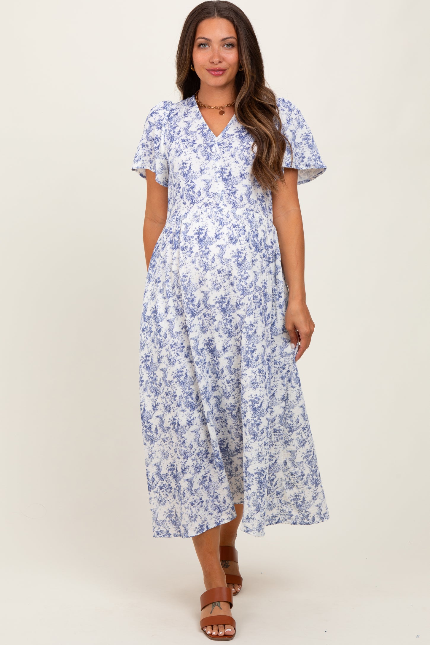 woman wearing a blue and white floral maternity dress with short sleeves and a v-neckline, showing her baby bump