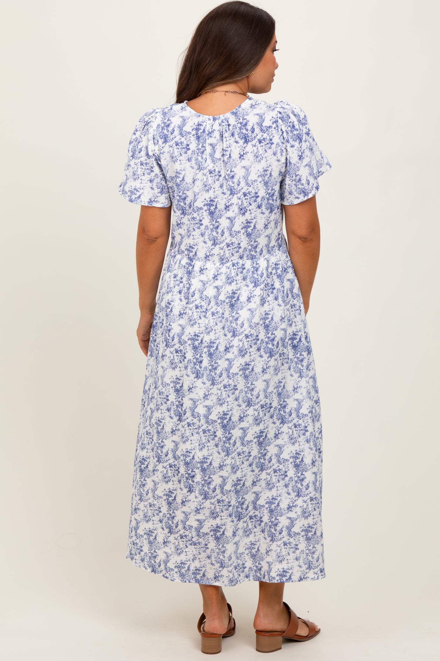 woman wearing a blue and white floral print maternity maxi dress, shown from the back