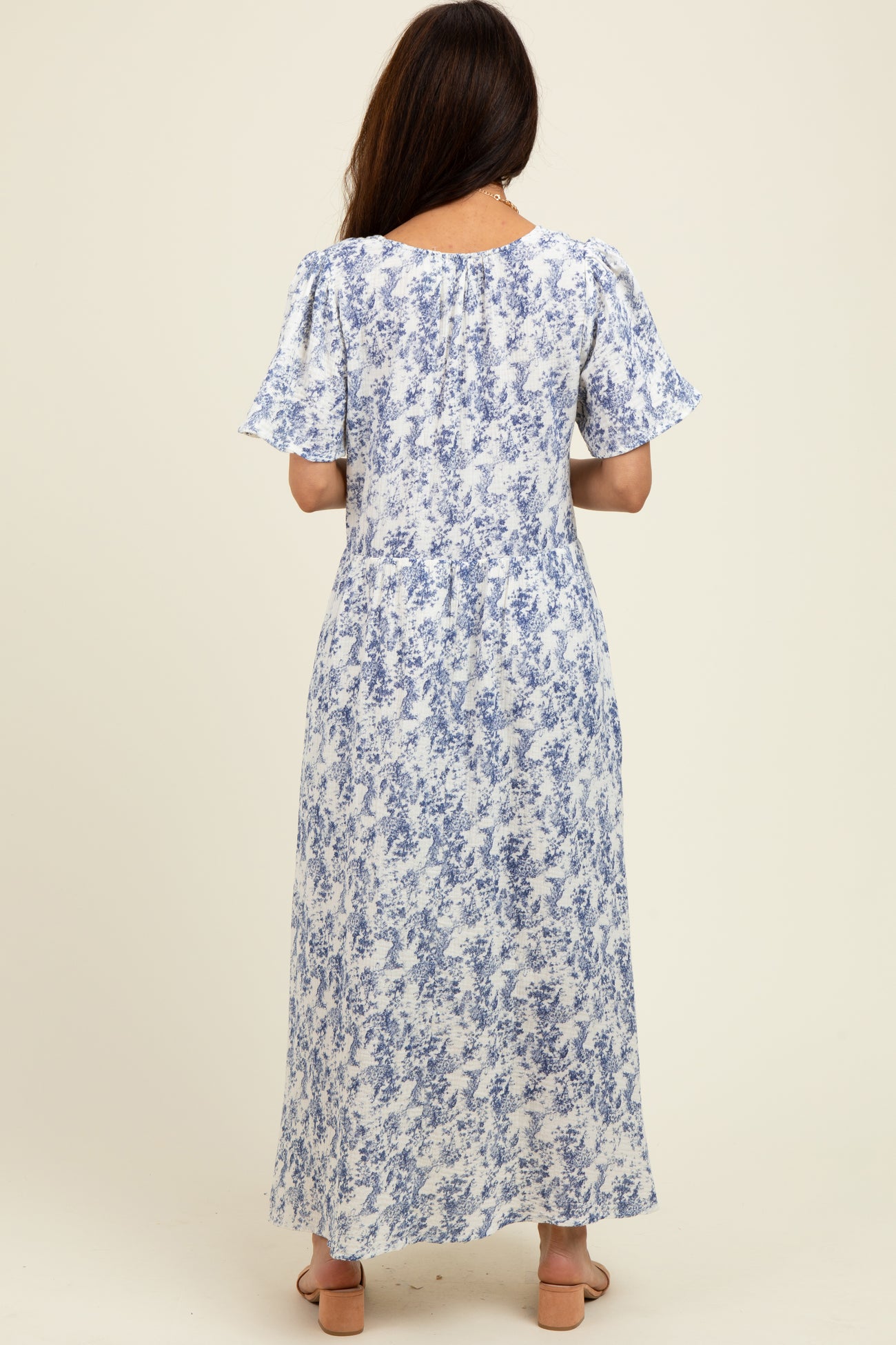 woman wearing a blue and white floral maxi dress with short sleeves, shown from the back