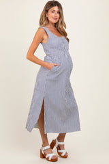 woman wearing a blue and white striped maternity maxi dress with pockets and side slits, showing her baby bump