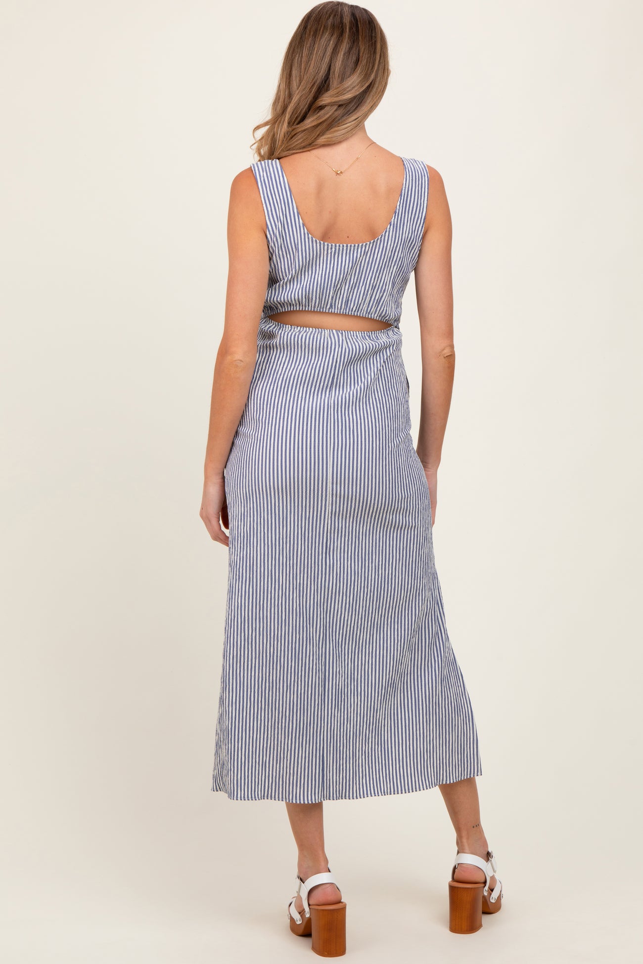 woman wearing a blue and white striped backless maternity dress with a fitted bodice and flowy skirt