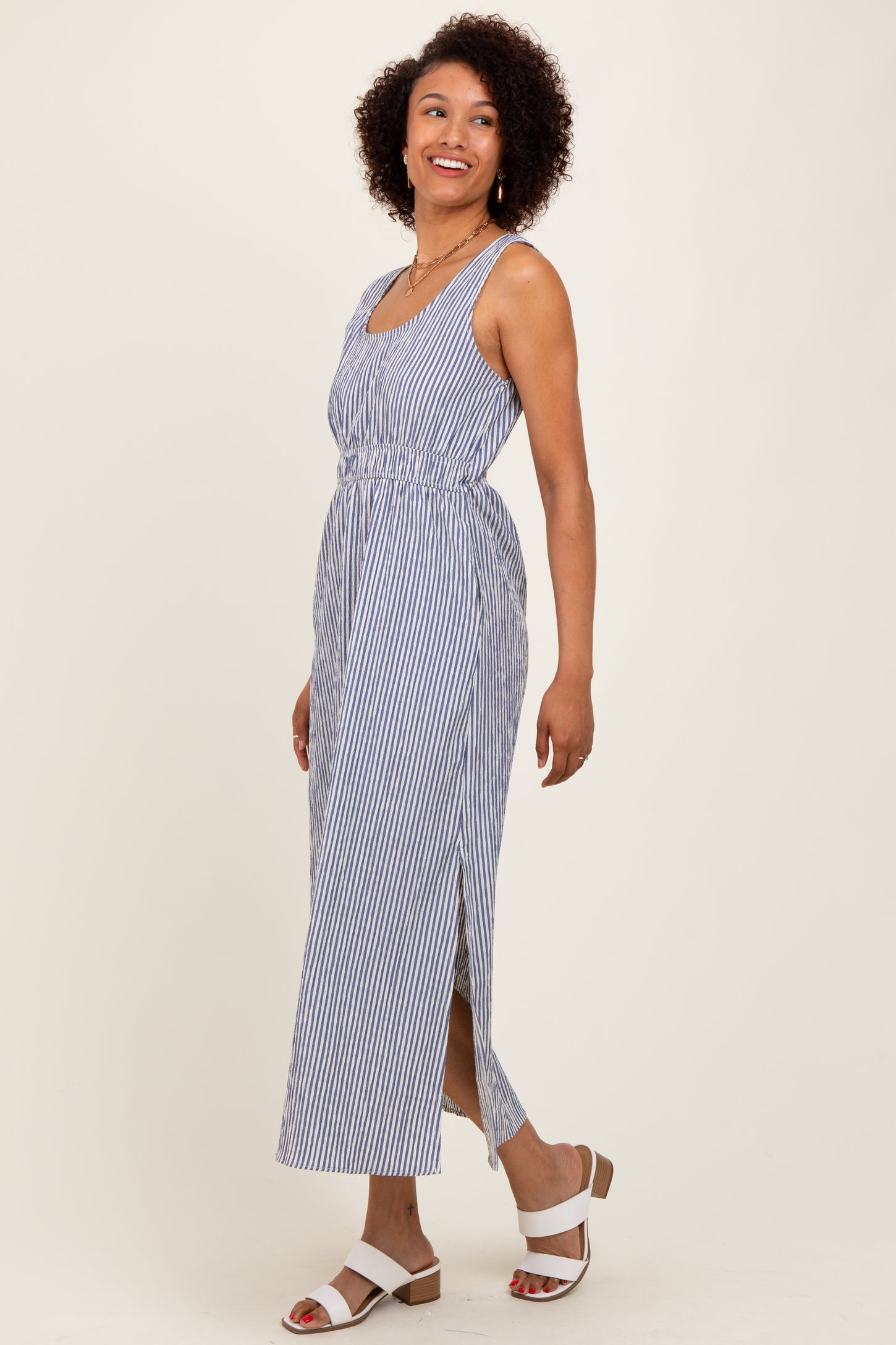 woman wearing a navy and white striped sleeveless maxi dress with a tie waist and side slits
