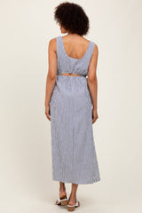woman wearing a striped blue and white sleeveless maxi dress with an open back and cinched waist