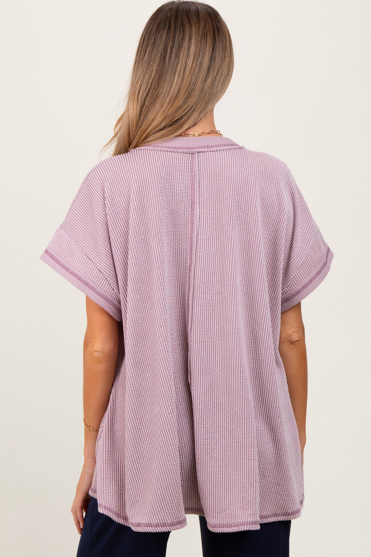 woman wearing a light purple oversized maternity top with short sleeves and a relaxed fit