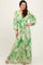 woman wearing a green floral maxi dress with a deep v-neckline and puff sleeves, standing against a neutral background