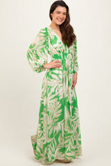 woman wearing a green maxi dress with a tropical leaf print and puff sleeves, styled with a smocked waist